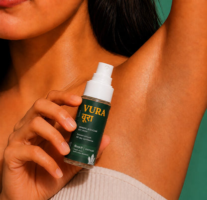 A woman holding the Vura Phitkari underarm spray beside a raised, bare underarm