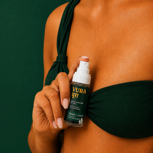 Vura Mineral Underarm Spray held in hand against a deep green background